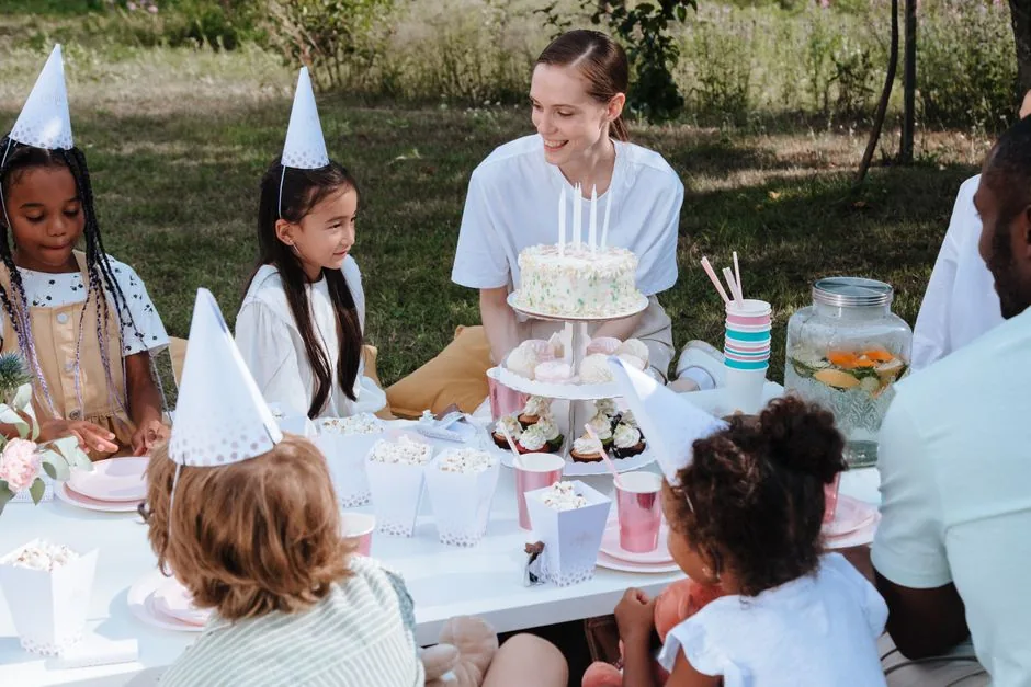 Children in party hats around a birthday table outdoors
