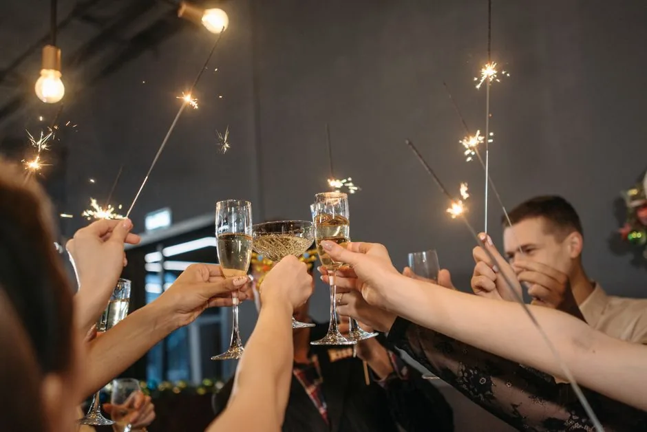 Group raising champagne glasses and sparklers at a party