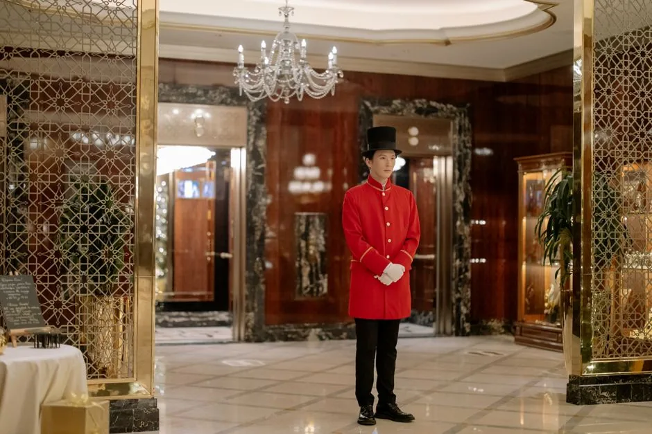 Doorman in a red uniform standing in a hotel lobby
