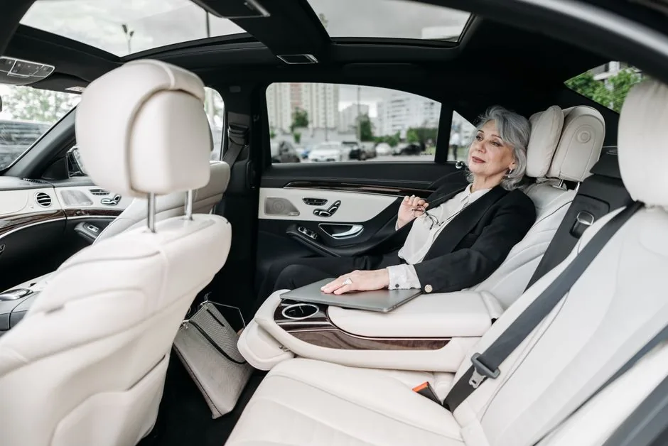 Passenger relaxing in the back seat of a luxury sedan with white leather seats