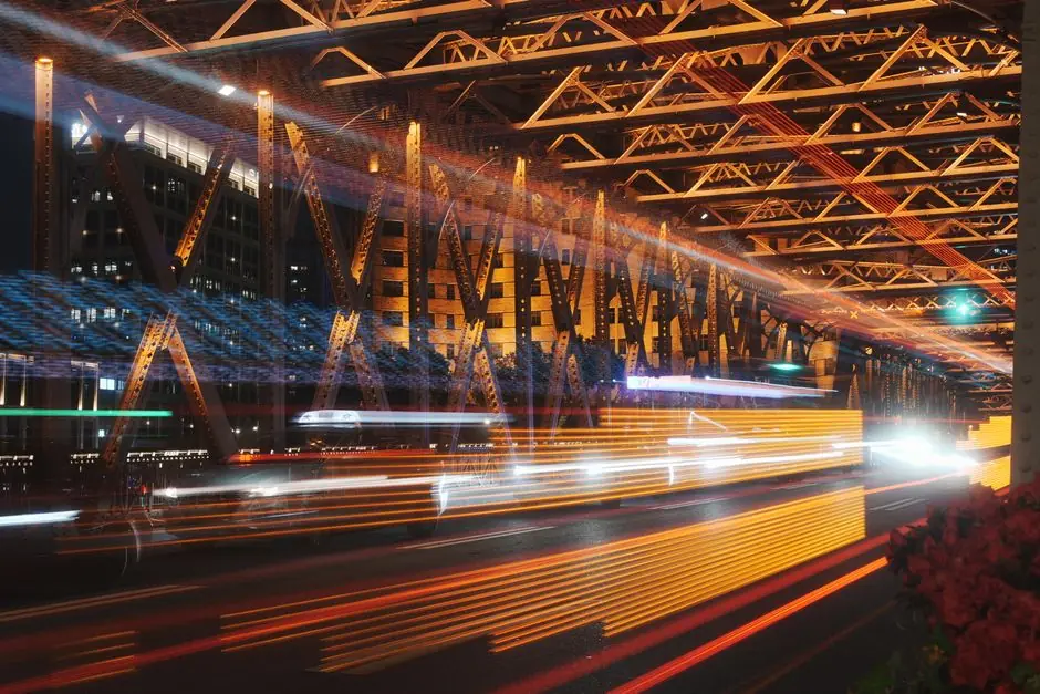Traffic light trails beneath a steel bridge at night