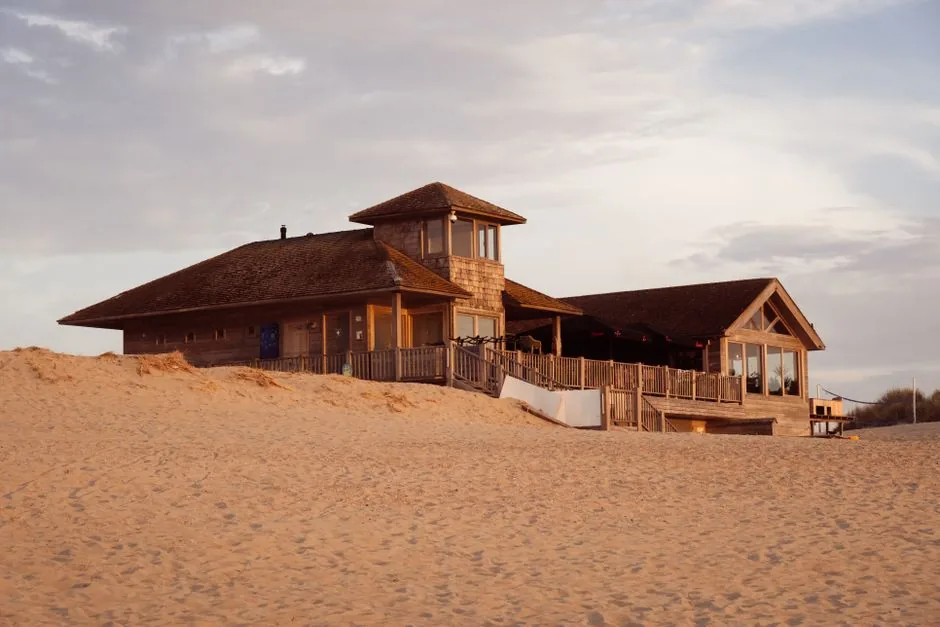 Wooden beach house on the sand dunes under a cloudy sky