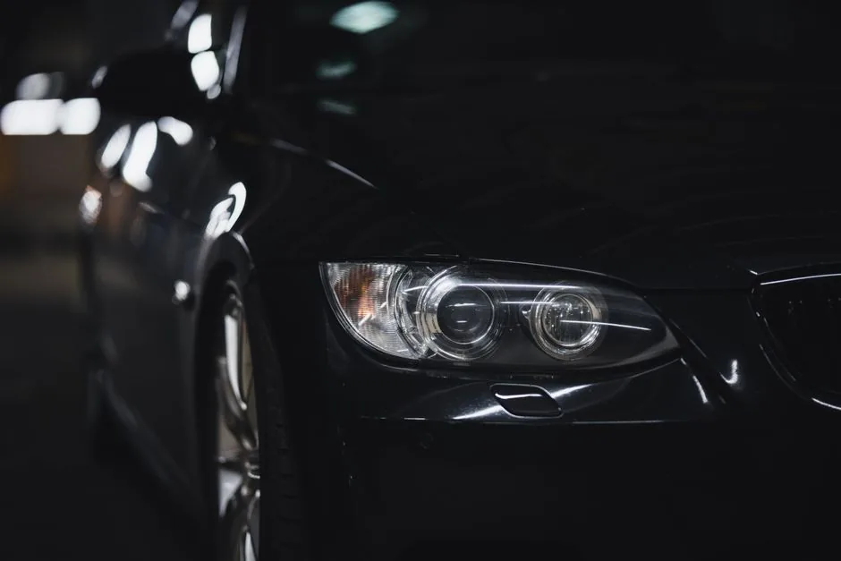 Headlight of a dark car glowing at night